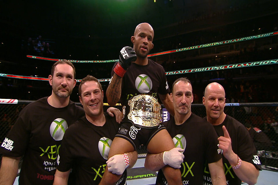 Two men holding the best UFC fighter in flyweight history Demetrious Johnson